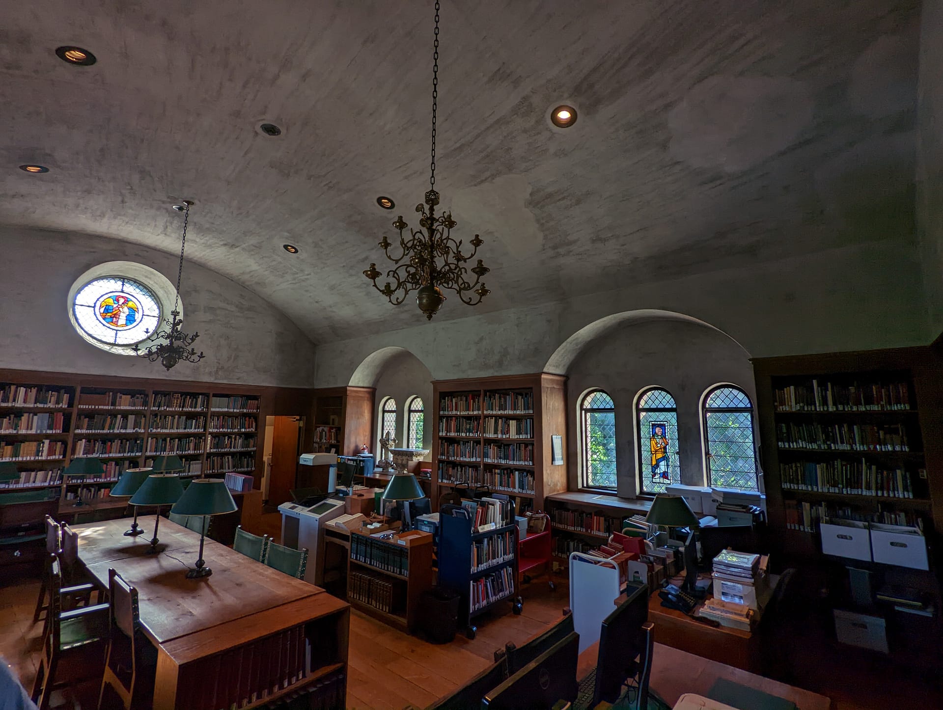 The space has a vaulted ceiling with walls of books and stained glass windows